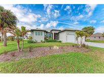 Charming single Gathering home featuring a lush green lawn and complemented by swaying palm trees at 237 W Pine Valley Ln, Rotonda West, FL 33947