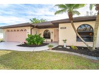 Charming home featuring an attached garage, arched windows and tropical landscaping at 2948 Briant St, North Port, FL 34287