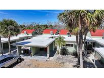 Charming townhouse featuring a covered parking area and a vibrant red roof, surrounded by lush palm trees at 2985 N Beach Rd # C6-2, Englewood, FL 34223