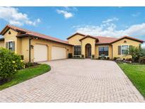 Charming, well-maintained single-story home with a tile roof, lush landscaping, and a brick driveway at 10953 Bullrush Dr, Venice, FL 34293