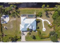 Aerial view of home with screened-in pool and patio, fire pit, and lush landscaping at 14157 Kewanee Ln, Port Charlotte, FL 33981