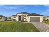Beautiful home featuring a well-manicured lawn, paver driveway, and neutral color palette at 15044 Acorn Cir, Port Charlotte, FL 33981
