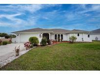 Charming one-story home with a well-manicured lawn and an attached garage, enhanced by colorful landscaping at 184 Eppinger Dr, Port Charlotte, FL 33953
