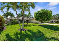 Lush front yard with palm trees leading to a well-maintained, one-story home with a tile roof at 2160 Palm Tree Dr, Punta Gorda, FL 33950