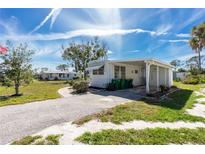 Charming mobile home featuring an extended driveway, covered porch, and well-maintained lawn, offering comfortable living at 3210 Holly Ave, Englewood, FL 34224