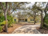 Charming yellow home featuring a welcoming porch and a lush, tree-lined front yard at 4050 Rock Creek Dr, Port Charlotte, FL 33948