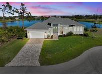 Beautiful exterior of home with well-manicured lawn, lovely landscaping, and lake view at sunset at 5 Reef Ct, Placida, FL 33946