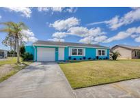 Charming turquoise home featuring a white garage door, front door, white trimmed windows, and a manicured front lawn at 6264 Drucker Cir, Port Charlotte, FL 33981