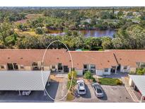 Aerial view of condo complex with covered parking and pond in a landscaped setting at 6796 Gasparilla Pines Blvd # 40, Englewood, FL 34224