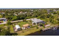 Stunning aerial view of a waterfront property with a private dock, pool, and beautifully landscaped yard at 14382 Lillian Cir, Port Charlotte, FL 33981