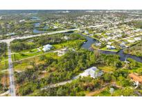 Expansive aerial view of a waterfront property with lush greenery and a winding canal at 150 N Oxford Dr, Englewood, FL 34223