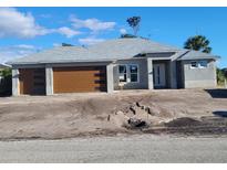 New home featuring a stucco exterior, gray roof, and a two-car garage with a modern wood-look door at 418 Rotonda Cir, Rotonda West, FL 33947