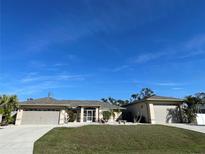 Charming single-story home with a well-manicured lawn, beige exterior and attached two-car garage at 5262 Weatherton St, North Port, FL 34288