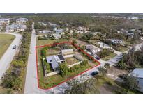 This aerial view showcases a charming home with a fenced yard, outlined in red to show property lines and neighborhood setting at 2191 Williamsburg Way, Englewood, FL 34224