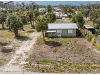 Charming home featuring a metal roof and a spacious, partially landscaped yard with mature palm trees at 7032 Duke St, Englewood, FL 34224