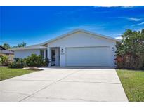 Charming single-story home with a well-manicured lawn and a spacious driveway leading to a two-car garage at 9265 Carnation Ave, Englewood, FL 34224