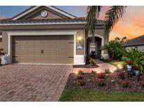 Inviting home featuring a brick driveway, meticulous landscaping, and a cozy two-car garage at 11417 Okaloosa Dr, Venice, FL 34293