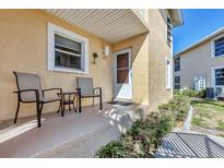 Cozy porch with seating and front door to a yellow home at 6610 Gasparilla Pines Blvd # 113, Englewood, FL 34224