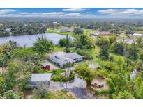 Expansive aerial view of home featuring lush landscaping, lake, guest houses, and outbuildings on a picturesque lot at 730 Buckskin Ct, Englewood, FL 34223