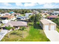 Expansive aerial view of a tan home with lush lawn, detached garage, and tropical landscaping at 9260 Saint Catherine Ave, Englewood, FL 34224