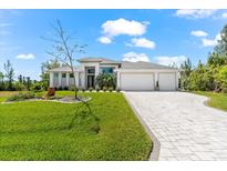 Stunning single-Gathering home with a well-manicured lawn and a paved driveway leading to a three-car garage at 10491 Sarasota Rd, Port Charlotte, FL 33981