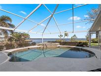 A screened in pool features a waterfall, with beautiful views of the water at 12432 Nova Ave, Port Charlotte, FL 33981