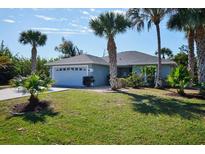 Charming single-story home with lush landscaping, palm trees, and a two-car garage at 127 Linda Lee Dr, Rotonda West, FL 33947