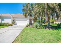 Charming home with a well-manicured lawn, mature palm trees, and a two-car garage at 14270 Reserve Ct, Port Charlotte, FL 33953
