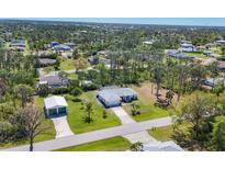 Aerial view of a single-Gathering home with a well-maintained lawn, mature trees, and a detached garage at 5258 Grassland Ter, Port Charlotte, FL 33981
