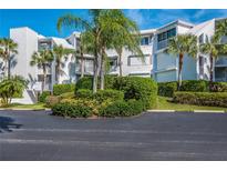 Exterior view of a white condo building surrounded by lush, manicured landscaping and tropical palm trees at 5858 Gasparilla Rd # Mm40, Boca Grande, FL 33921