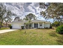 Charming single-story home featuring a manicured lawn, attached garage, and welcoming front entrance at 587 Viridian St, Englewood, FL 34223
