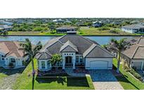 Beautiful exterior view of a one-story home featuring a tile roof, lush lawn, and waterfront access at 8144 Antwerp Cir, Port Charlotte, FL 33981