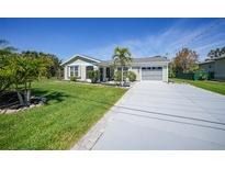 Charming home with well-manicured lawn, palm trees, and a long driveway leading to the garage at 9350 Prospect Ave, Englewood, FL 34224