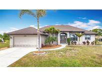 Charming single-story home with a manicured lawn, a two-car garage, and lush landscaping at 12605 Bacchus Rd, Port Charlotte, FL 33981