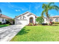 Charming home with lush lawn, palm trees, and a driveway leading to a two-car garage at 14236 Silver Lakes Cir, Port Charlotte, FL 33953