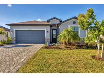 Charming single-story home with gray paint, a well-manicured lawn, and a paver driveway at 1824 Saddlewood Cir, Port Charlotte, FL 33953