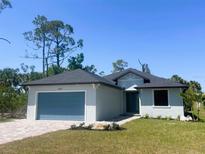 Charming one-story home with blue garage door and landscaped front yard at 220 Jennifer Dr, Rotonda West, FL 33947