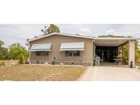 Tan home with a covered carport and awning-covered windows complemented by small decorative pineapples on the lawn at 3021 Holly Ave, Englewood, FL 34224