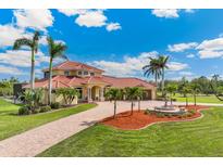 Stunning two-story home featuring lush landscaping, a fountain, and a brick driveway at 3700 Como St, Port Charlotte, FL 33948