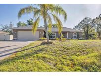 Charming single-story home with a well-maintained lawn and a palm tree in the front yard at 6345 Bodmin Ln, North Port, FL 34291