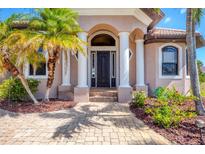 Elegant front entrance with stately columns, a brick walkway, and lush landscaping framing the doorway at 14810 Ingraham Blvd, Port Charlotte, FL 33981