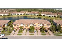 Scenic aerial view of townhomes by a lake with landscaped grounds and paver driveways at 20231 Lagente Cir, Venice, FL 34293
