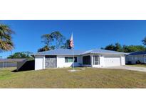 Charming single-story home featuring stone accents, an American flag, a well-maintained lawn, and a two-car garage at 2259 Lee Ter, Port Charlotte, FL 33952