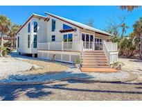 Charming coastal home featuring a spacious deck, modern design, and white picket fence at 4078 N Beach Rd, Englewood, FL 34223
