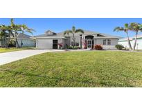 Charming one-story home featuring a well-manicured lawn, mature palm trees, and an attached two-car garage at 431 Rotonda Cir, Rotonda West, FL 33947