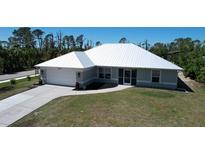Beautiful single-story home featuring a modern metal roof, well-maintained lawn, and an attached two-car garage at 7499 Clearwater St, Englewood, FL 34224