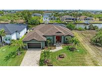 Beautiful home exterior featuring lush landscaping, a well-manicured lawn, and a paver driveway leading to an attached two-car garage at 8304 Antwerp Cir, Port Charlotte, FL 33981