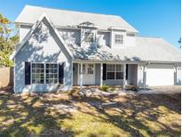Charming two-story home featuring a symmetrical facade, white trim, and a well-maintained front lawn and an attached garage at 1104 Larchmont Dr, Englewood, FL 34223