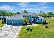 Beautiful single-Gathering home with lush lawn, paver driveway, and light blue exterior paint at 13443 Boabadilla Ln, Port Charlotte, FL 33981