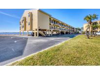 The exterior view of the building shows covered parking and a glimpse of the water in the background at 14459 River Beach Dr # 122, Port Charlotte, FL 33953